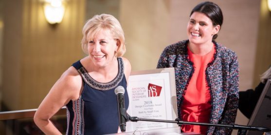 Professor Kaufman smiles at an awards podium next to a woman in a black blazer