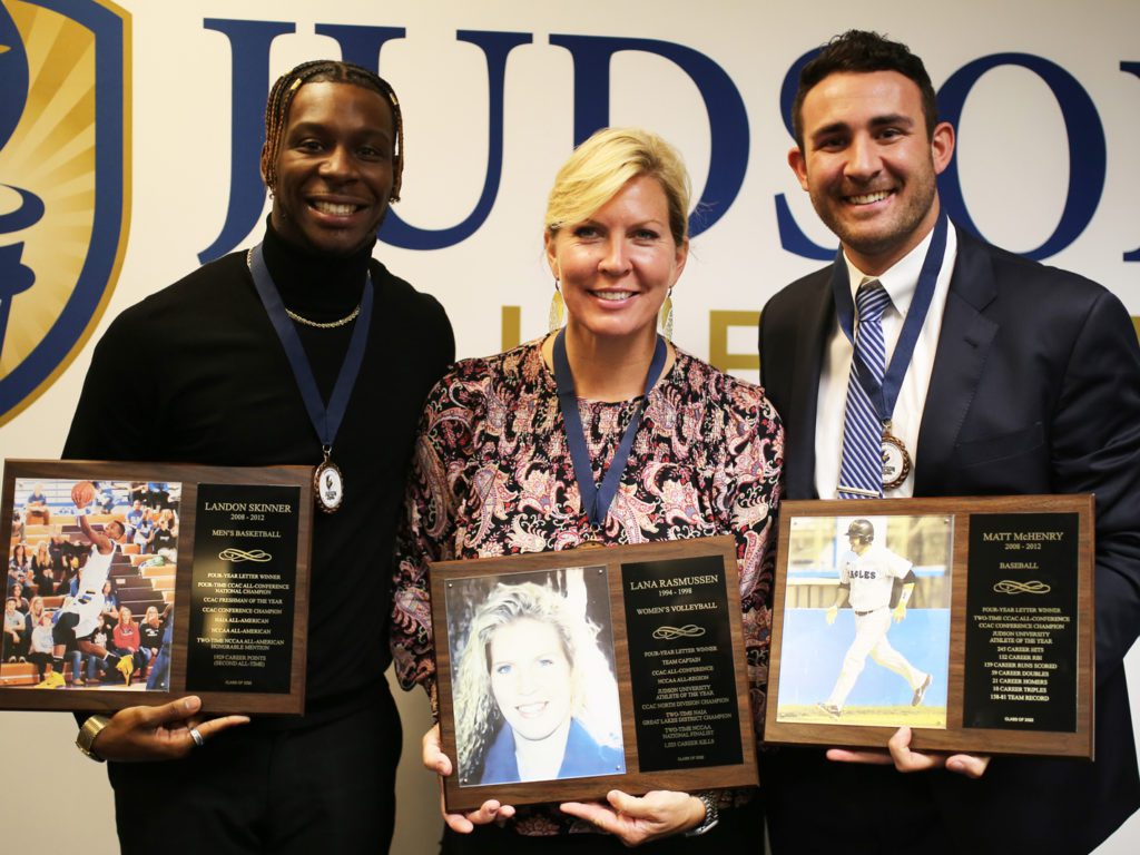 Two men and one woman holding awards